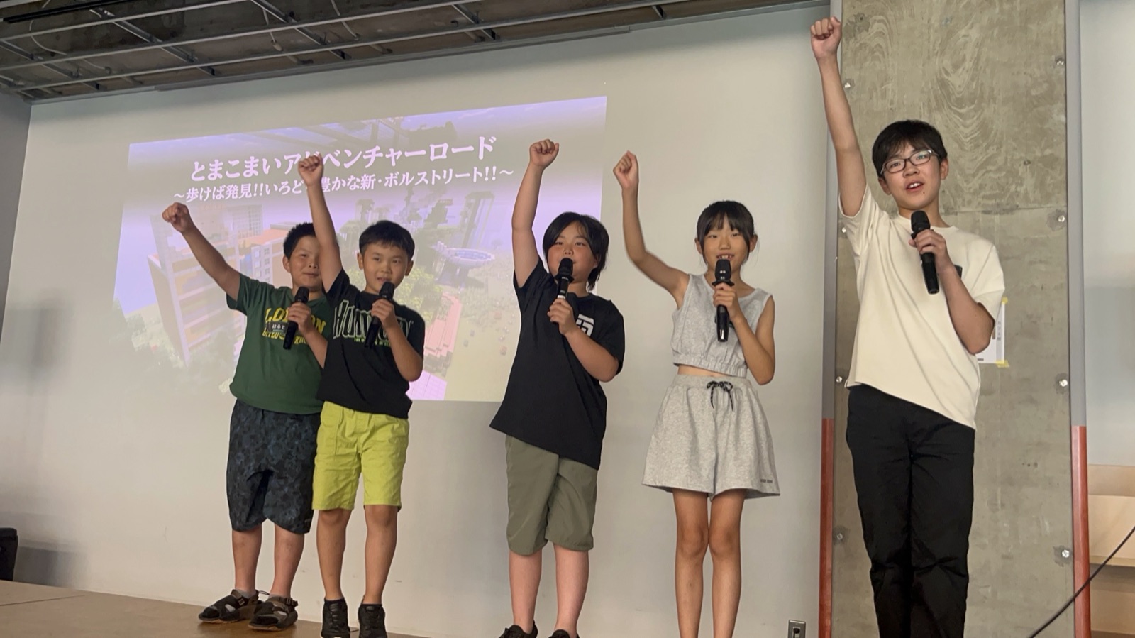 苫小牧市の発表会のフィナーレで、ステージに並んでマイクを持ち、拳を突き上げる5人の子どもたち