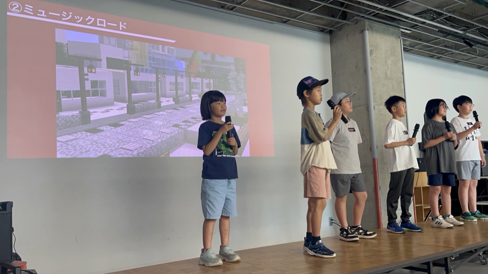 苫小牧市の発表会で、自分たちがマインクラフトでつくったまちをスクリーンに映して発表する子どもたち